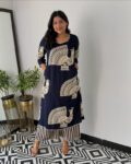 Women wearing navy blue peacock print cotton kurti set with striped pants, standing indoors on black and white geometric floor tiles”
