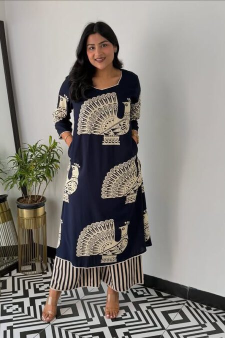 Women wearing navy blue peacock print cotton kurti set with striped pants, standing indoors on black and white geometric floor tiles”