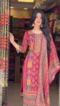 Woman wearing a vibrant red kurta pant and dupatta set with mirror work and traditional temple motifs, perfect for festive occasions.