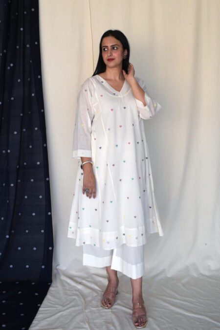 Model wearing a white cotton kurta pant set with multi-color heart embroidery, styled for casual ethnic summer wear.