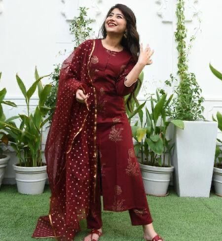 Woman wearing a maroon printed kurta set with matching pants and dupatta, styled for festive or traditional events.