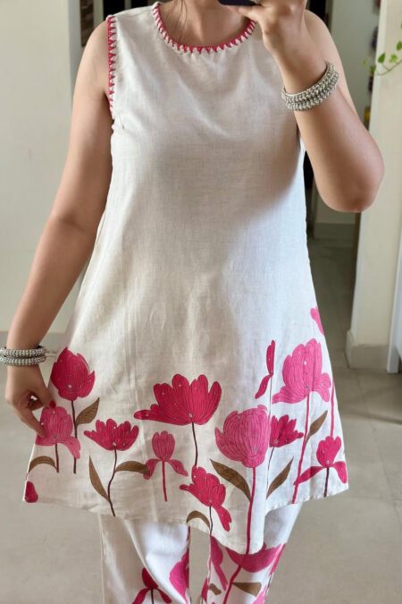 Woman wearing a white cotton sleeveless kurti set with pink floral block print, perfect summer ethnic wear for women.