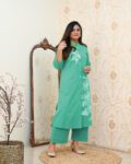 Woman wearing a mint green cotton kurta with white floral prints and straight-fit matching pants – modern ethnic wear with elegant design and side pockets.