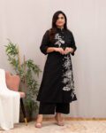 Woman wearing a black cotton kurta with white floral print, front buttons, and matching straight pants – stylish ethnic kurti pant set for women.