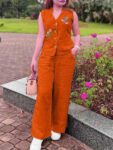 Woman wearing a rust orange sleeveless embroidered cotton co-ord set with wide-leg pants in a garden.