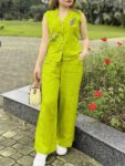 Woman wearing a lime green embroidered sleeveless cotton co-ord set with palazzo pants in a garden.
