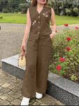 Woman wearing a brown sleeveless embroidered cotton kurti top with matching palazzo pants and a straw handbag, standing outdoors near red roses.