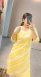 Woman wearing yellow and white striped cotton kurti with lace neckline, perfect for daily wear, casual outings, and summer ethnic fashion.