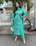“Elegant green ethnic kurti set with lace detailing, matching dupatta and pants worn by a woman outdoors”